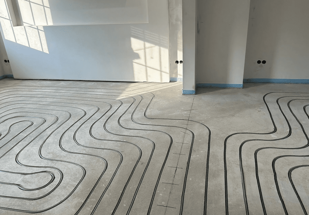 In den Estrich gefräste Kanäle, in denen ein Heizungsrohr für eine Fußbodenheizung verbaut wurde.